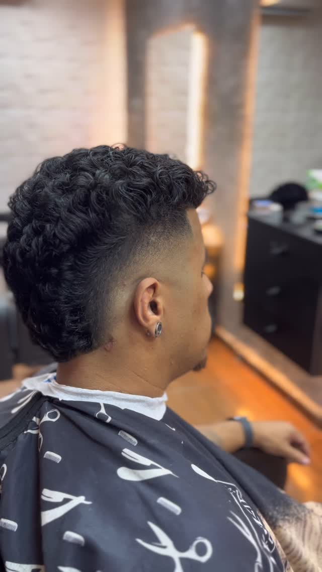 Mullet com cachos no topo e fade na nuca, vista de perfil